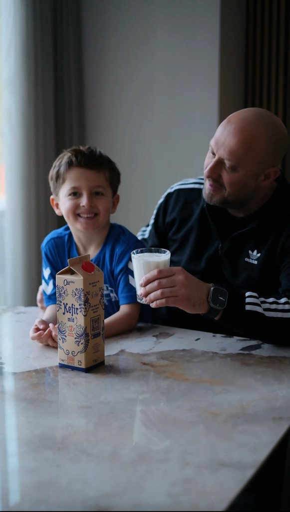 Familie genießt Quarki Kefir mild Ein Junge und ein Mann trinken gemeinsam Quarki Kefir mild am Tisch